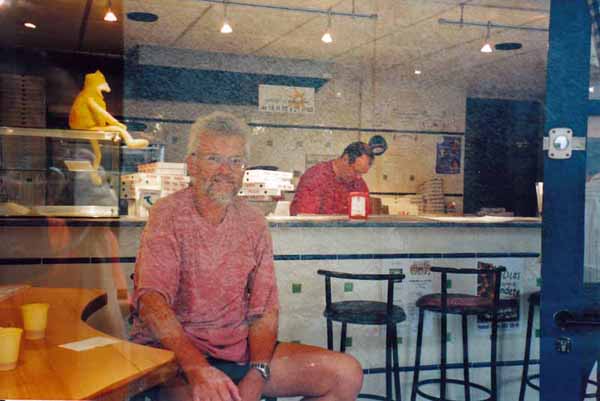 Walking in France: A "through the window photo" of the Morlaàs take-away pizza bar with our wonderful saviour in the background