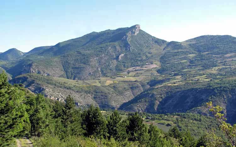 Walking in France: Looking down to the lavender farm and the gorge of the Eygues, with the great crag in the distance