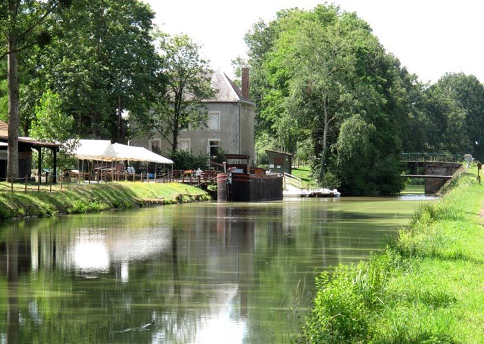 Walking in France: The museum at Magnette with a moored longboat on the canal